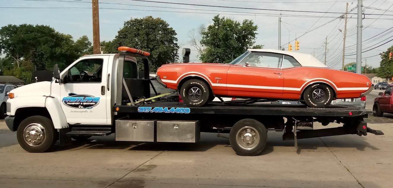 Fast Lane flatbed tow truck carrying a classic car in Indianapolis