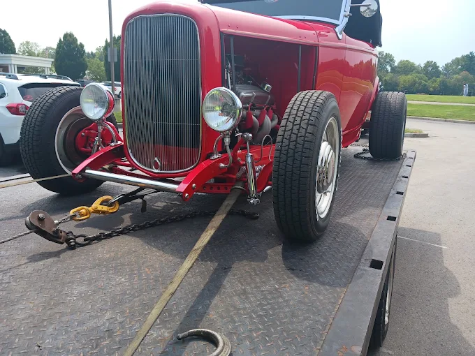 A classic vehicle loaded and secured with chains on a flatbed